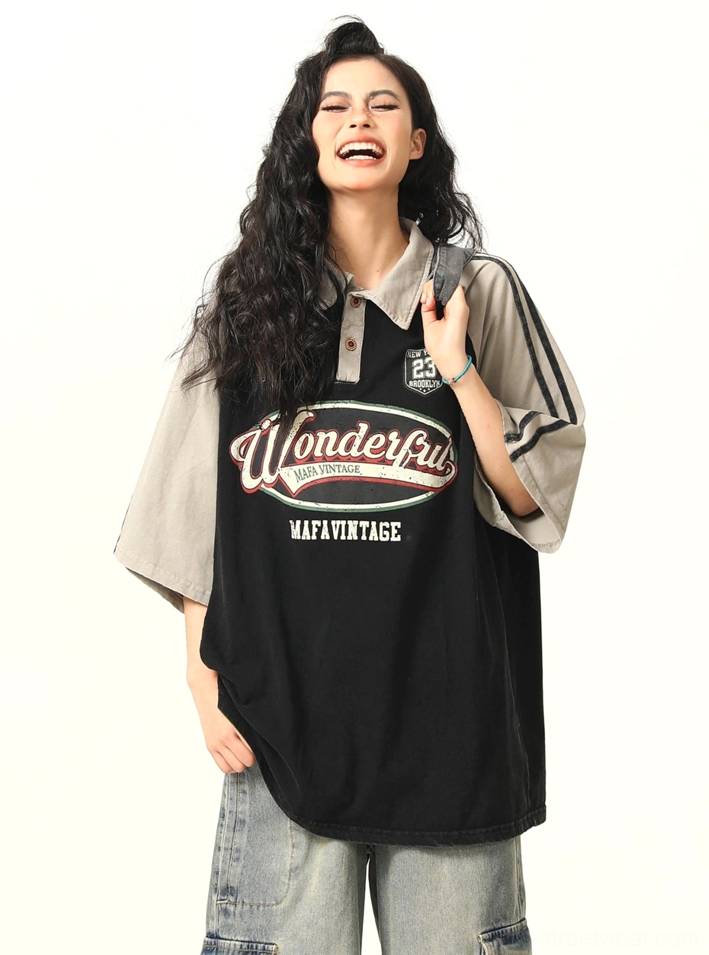 Black oversized retro graphic polo shirt with contrasting raglan sleeves and vintage streetwear design shown in a front three-quarter view