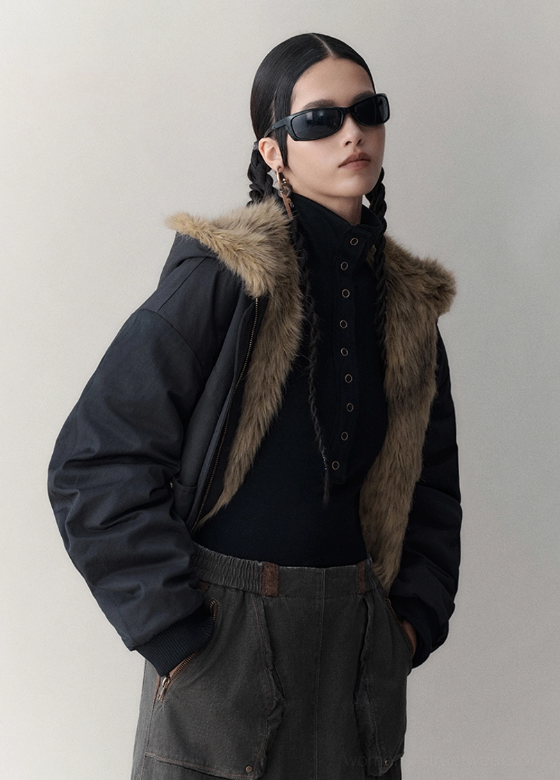 Model styling a black oversized reversible faux fur winter jacket with sunglasses and dark casual streetwear trousers