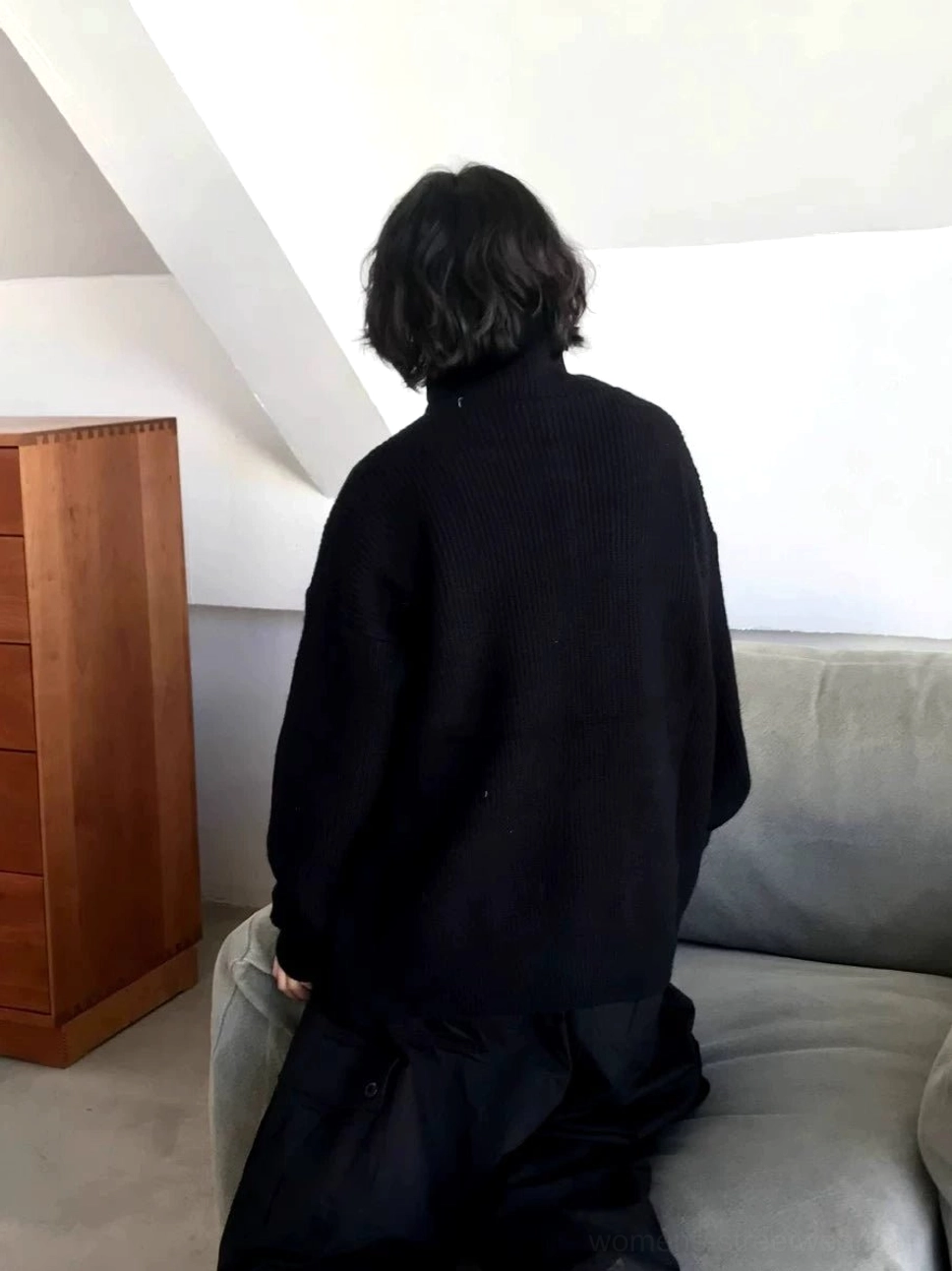 Back view of a black oversized ribbed knit cardigan sweater with loose silhouette and long sleeves