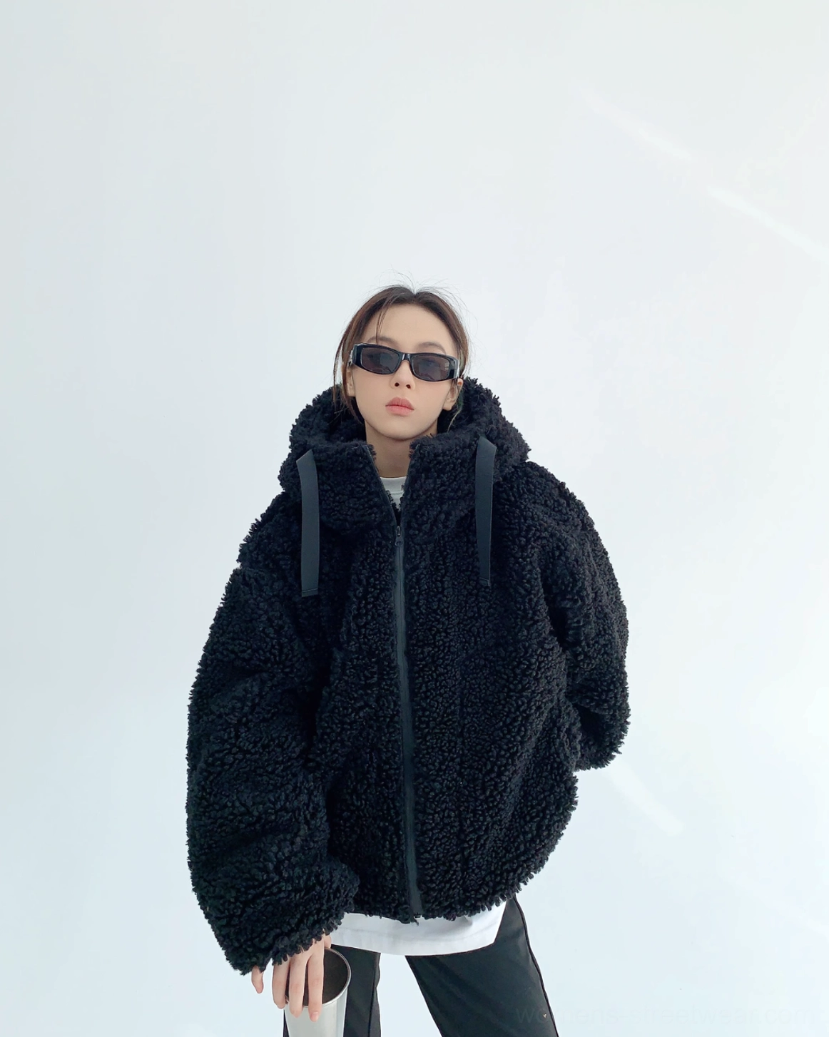 Front eye-level view of black oversized sherpa hoodie jacket with curly fleece, wide hood drawstrings, dropped shoulders, and voluminous sleeves
