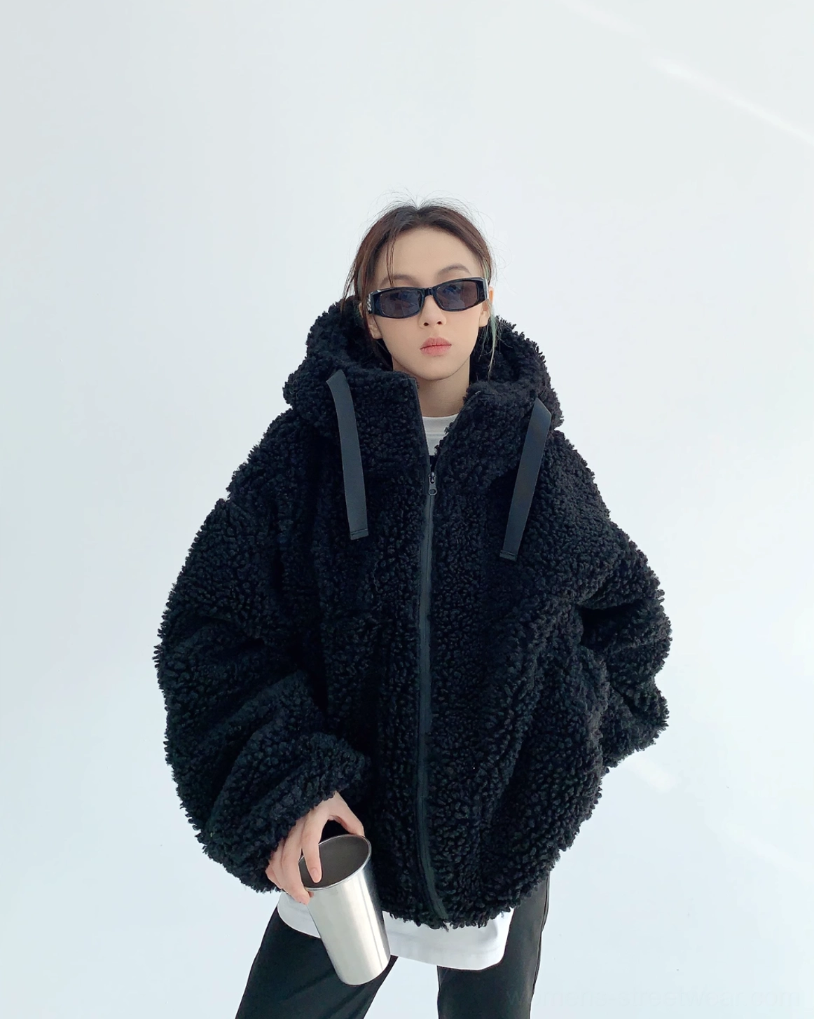 Front view of a woman wearing a black oversized sherpa teddy zip hoodie with fluffy curly fleece, dropped shoulders, hood drawstrings, and full front zipper