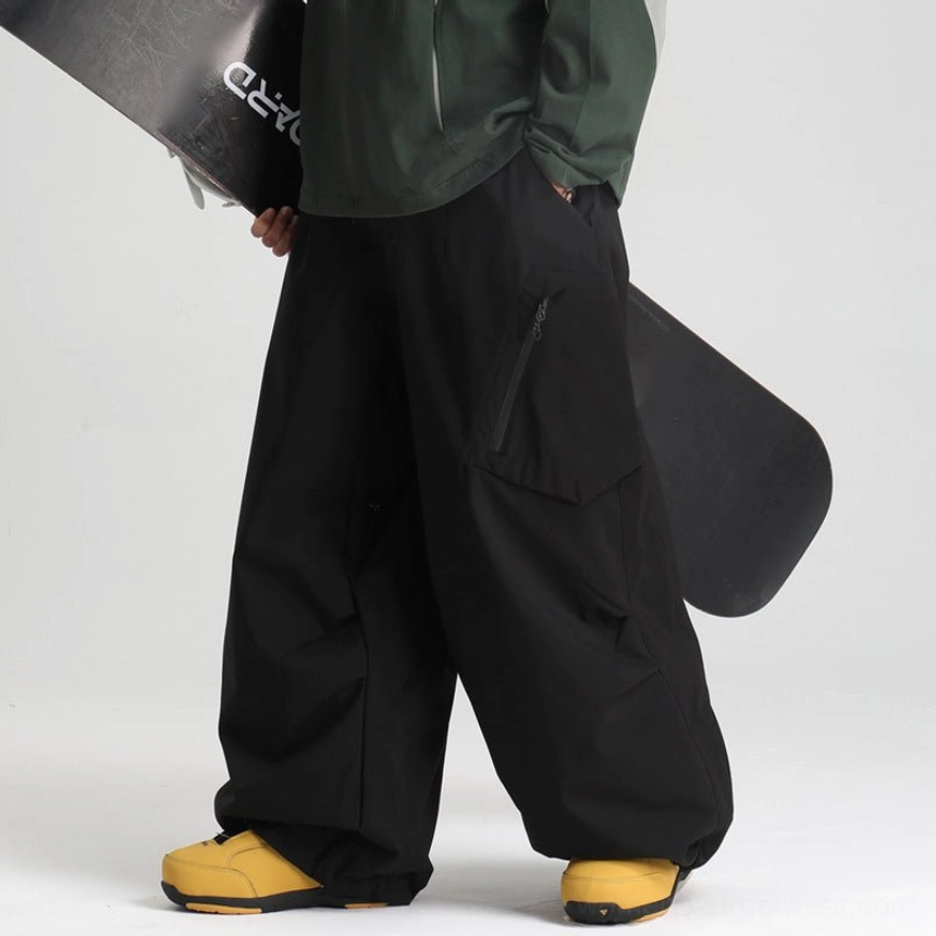 Black wide-leg snow pants side view male model dark green top yellow boots zippered thigh pocket streetwear