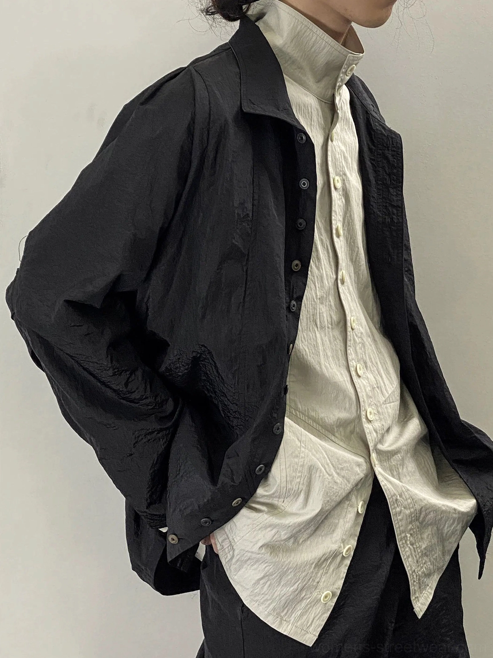 Black oversized stand collar shirt worn open over an off-white inner layer for layered Korean streetwear styling