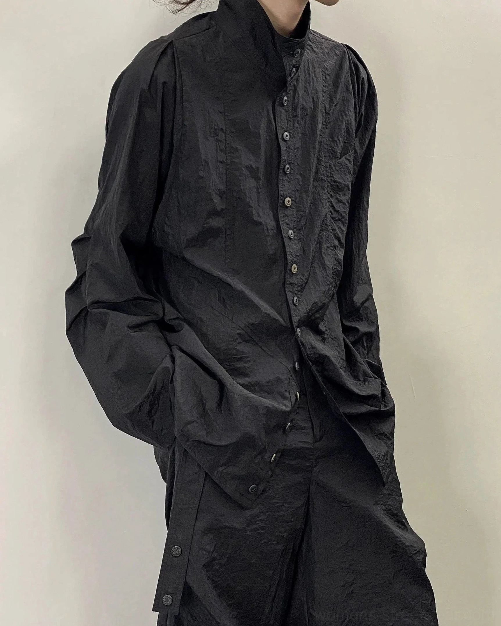 Side and rear view of black oversized stand collar button shirt with loose sleeves and side hem buttons