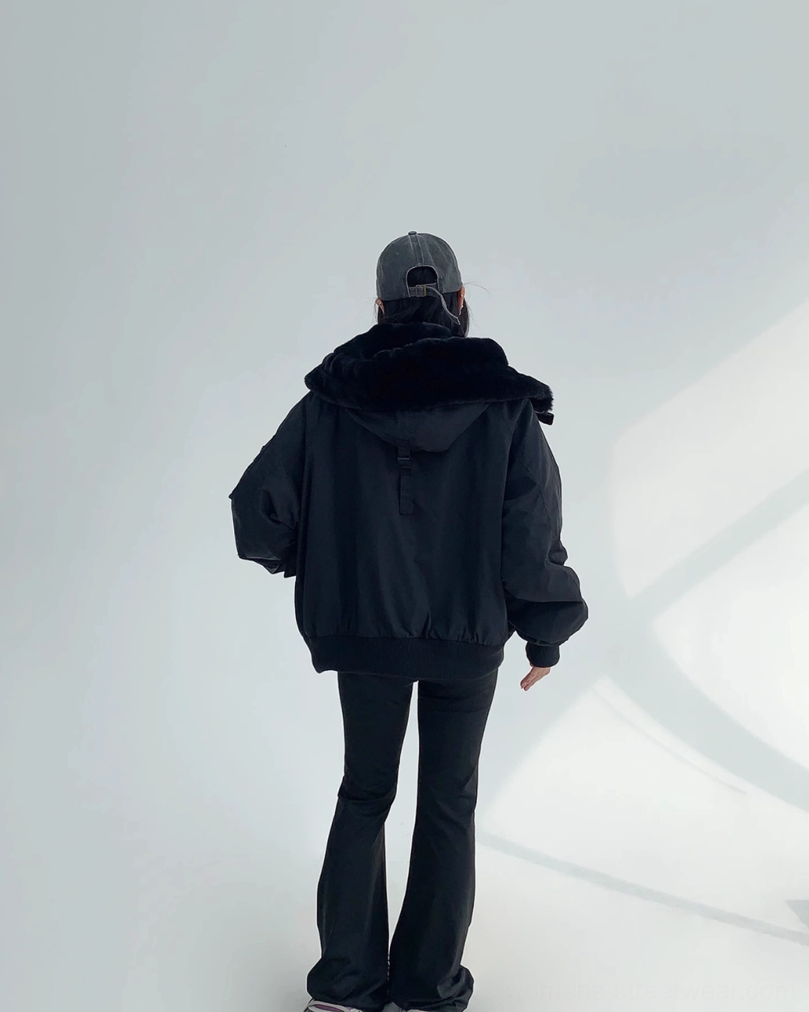 Black oversized streetwear bomber jacket with faux-shearling hood, relaxed fit, ribbed cuffs, and winter-ready texture