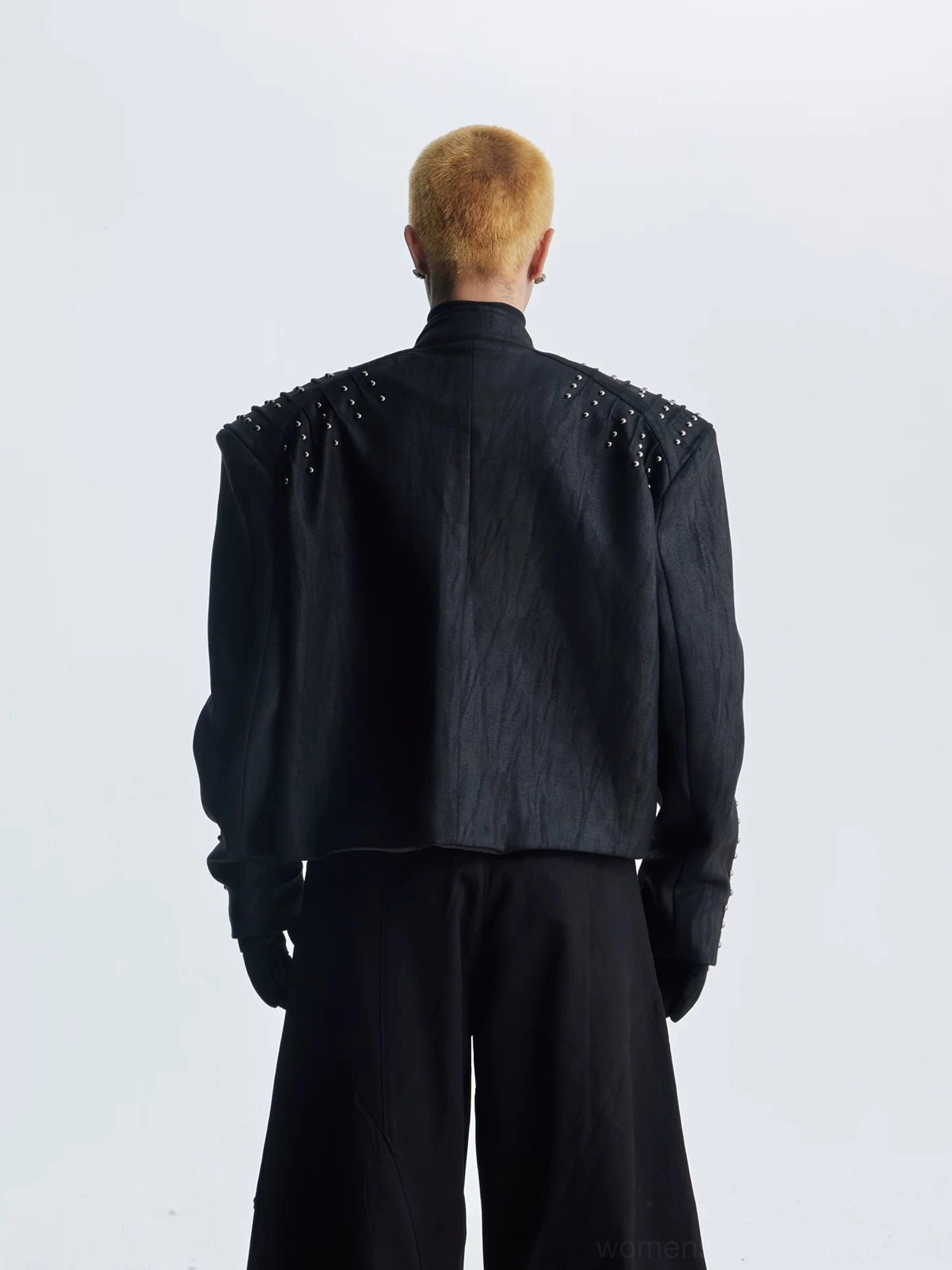 Rear view of black oversized studded moto jacket showing cropped loose fit and metallic shoulder rivet details