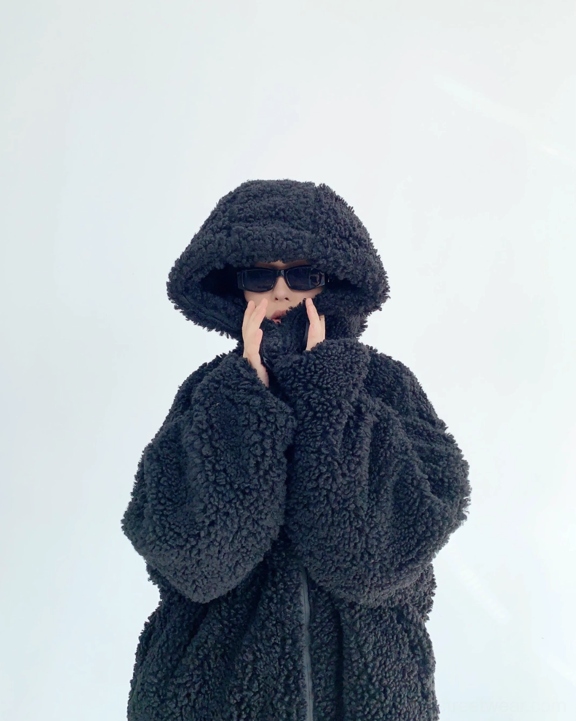 Three-quarter front view of black oversized teddy sherpa hoodie with hood up, full zip closure, soft fleece texture, and relaxed Korean streetwear silhouette