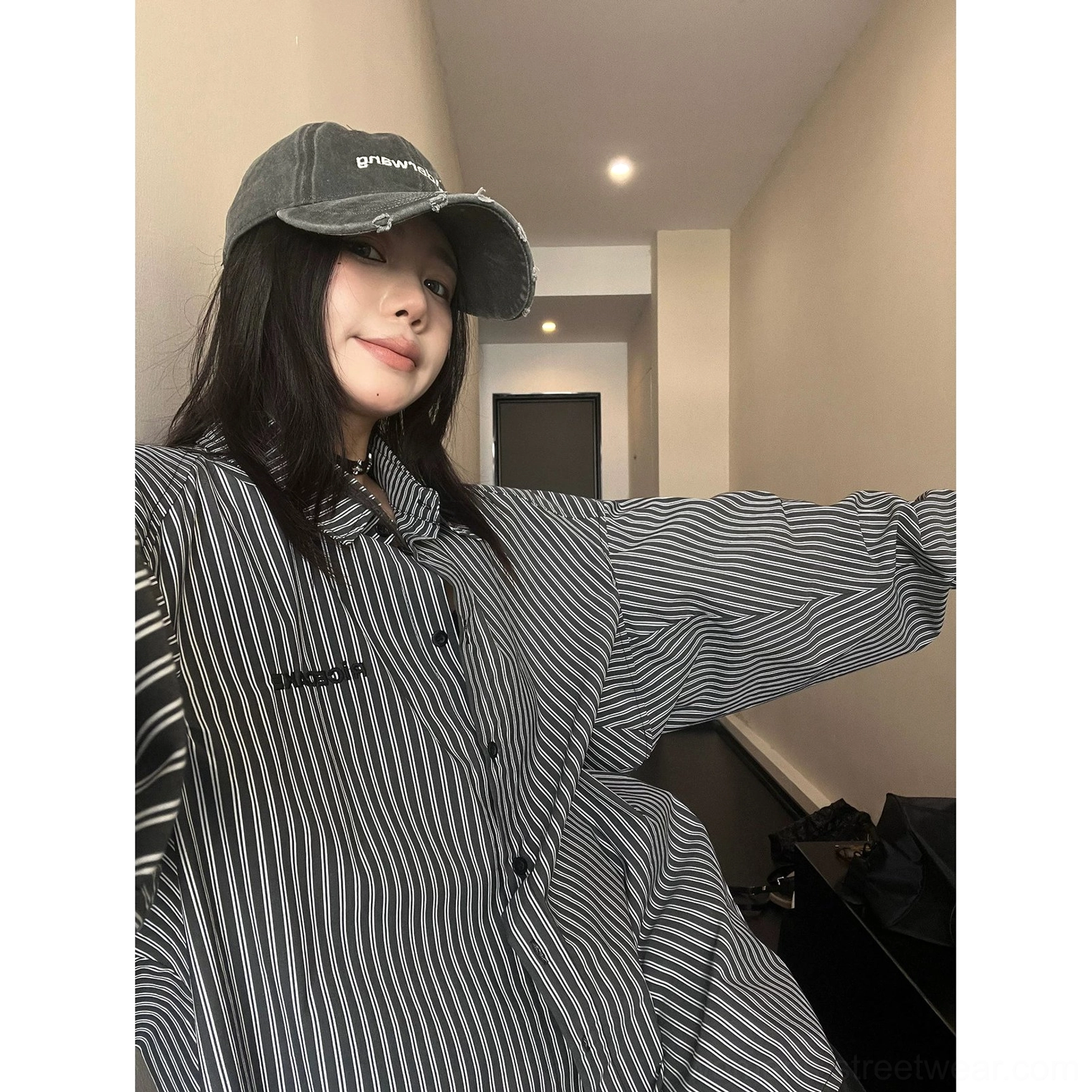 Front selfie view of black and white oversized vertical stripe long sleeve button-up shirt with loose sleeves