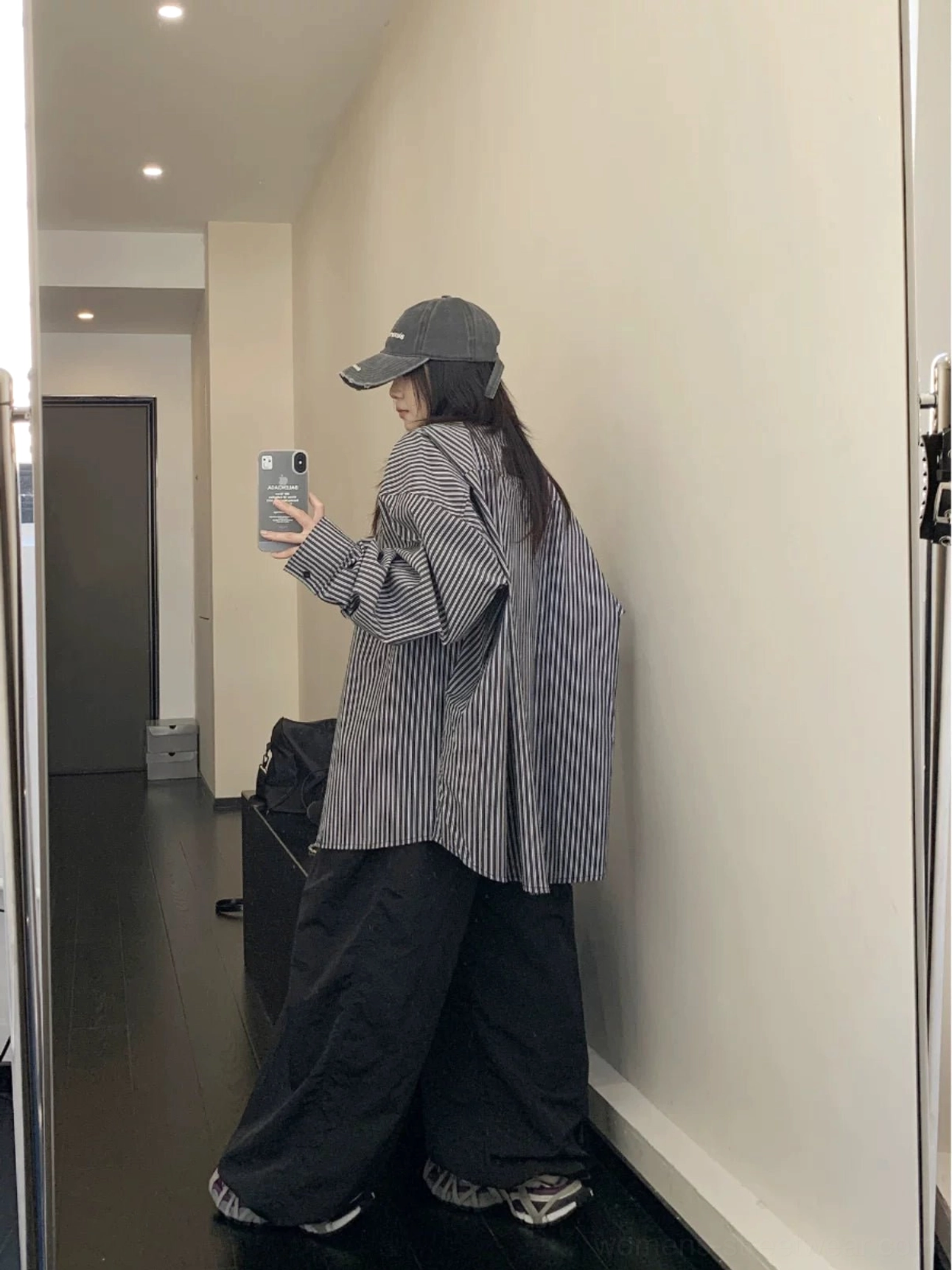 Full back view of black and white vertical stripe oversized long sleeve streetwear button-up shirt