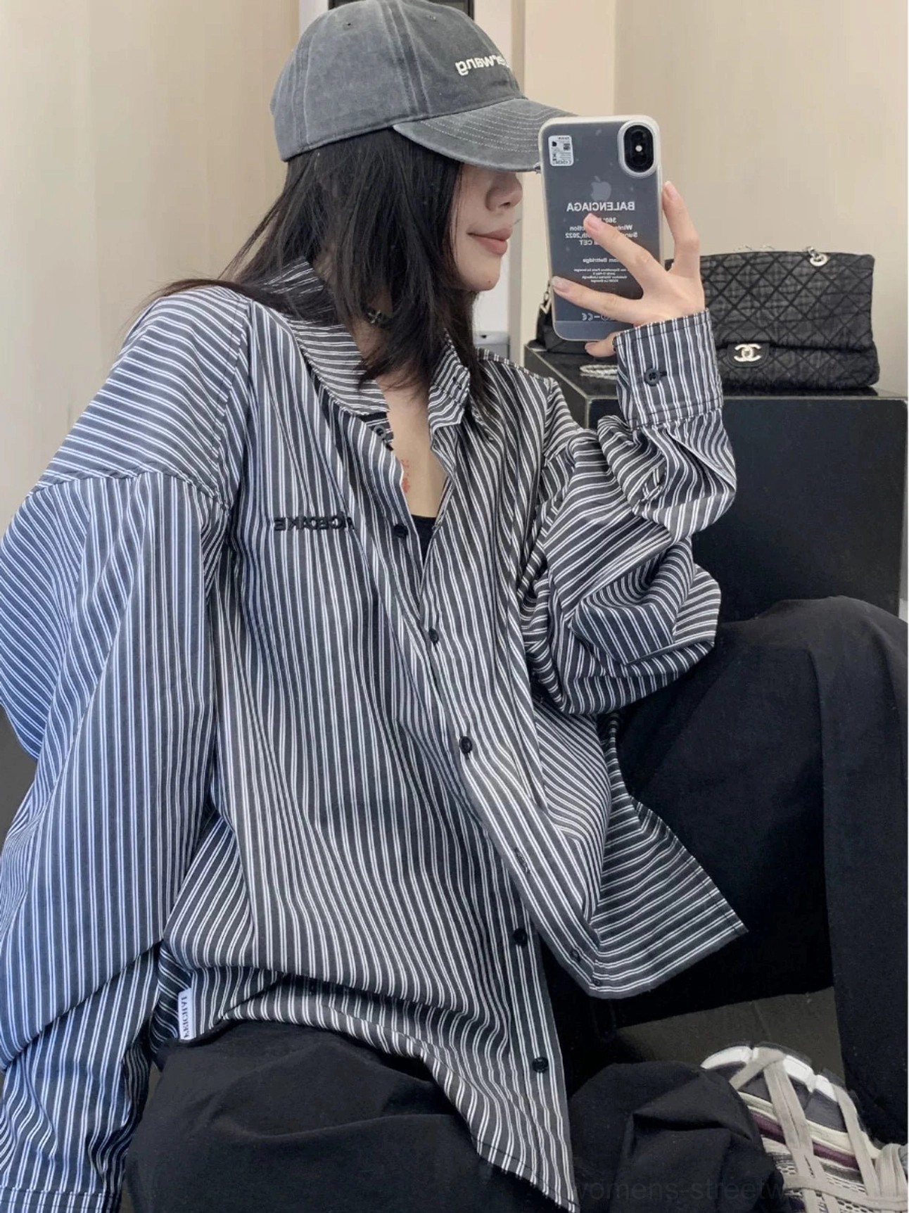 Black oversized vertical stripe cotton button-up streetwear shirt worn in a three-quarter side view with a gray cap