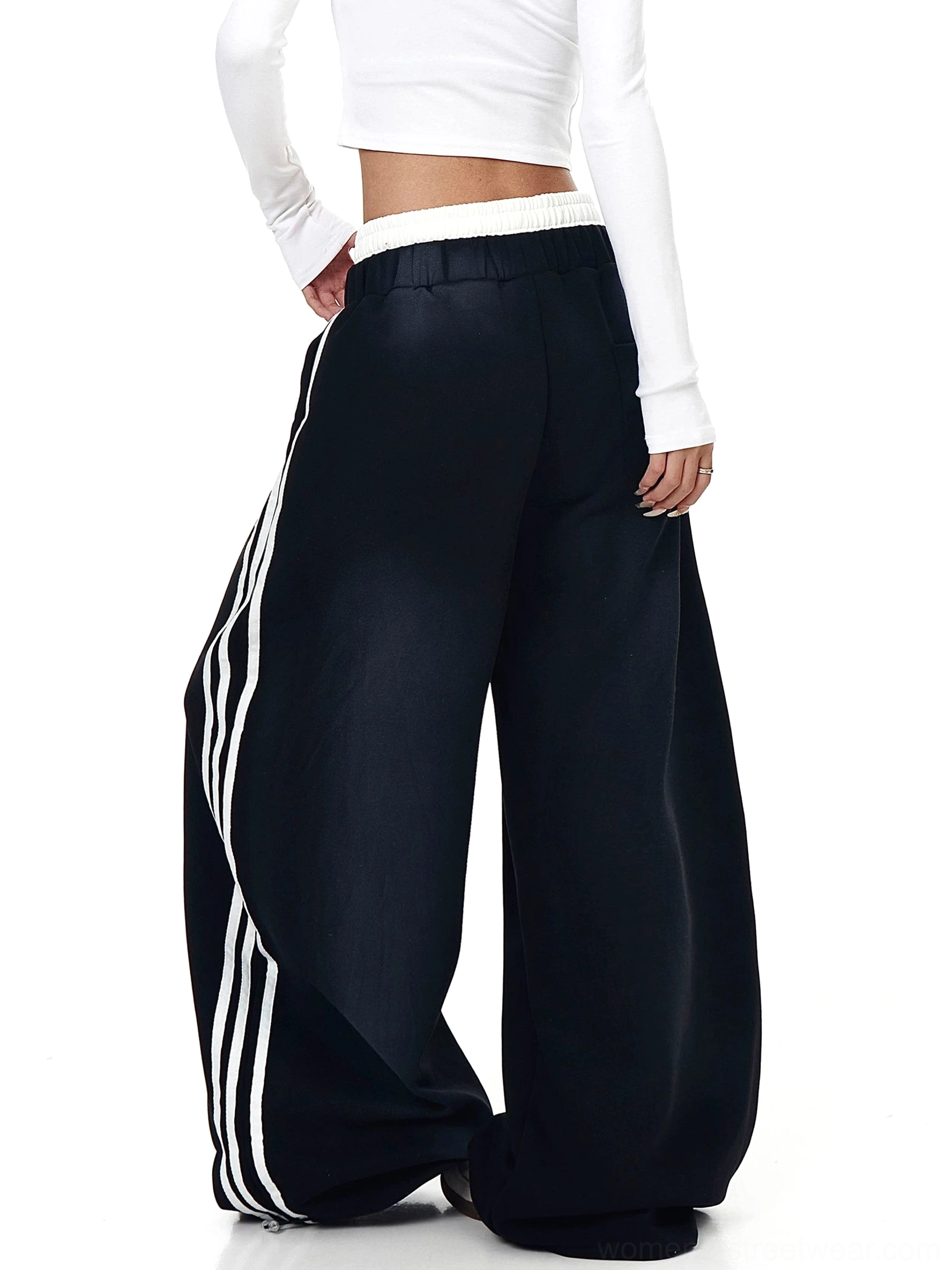 Back view of black oversized wide-leg graphic fleece sweatpants with clean rear panel, elastic waistband, and side stripe details