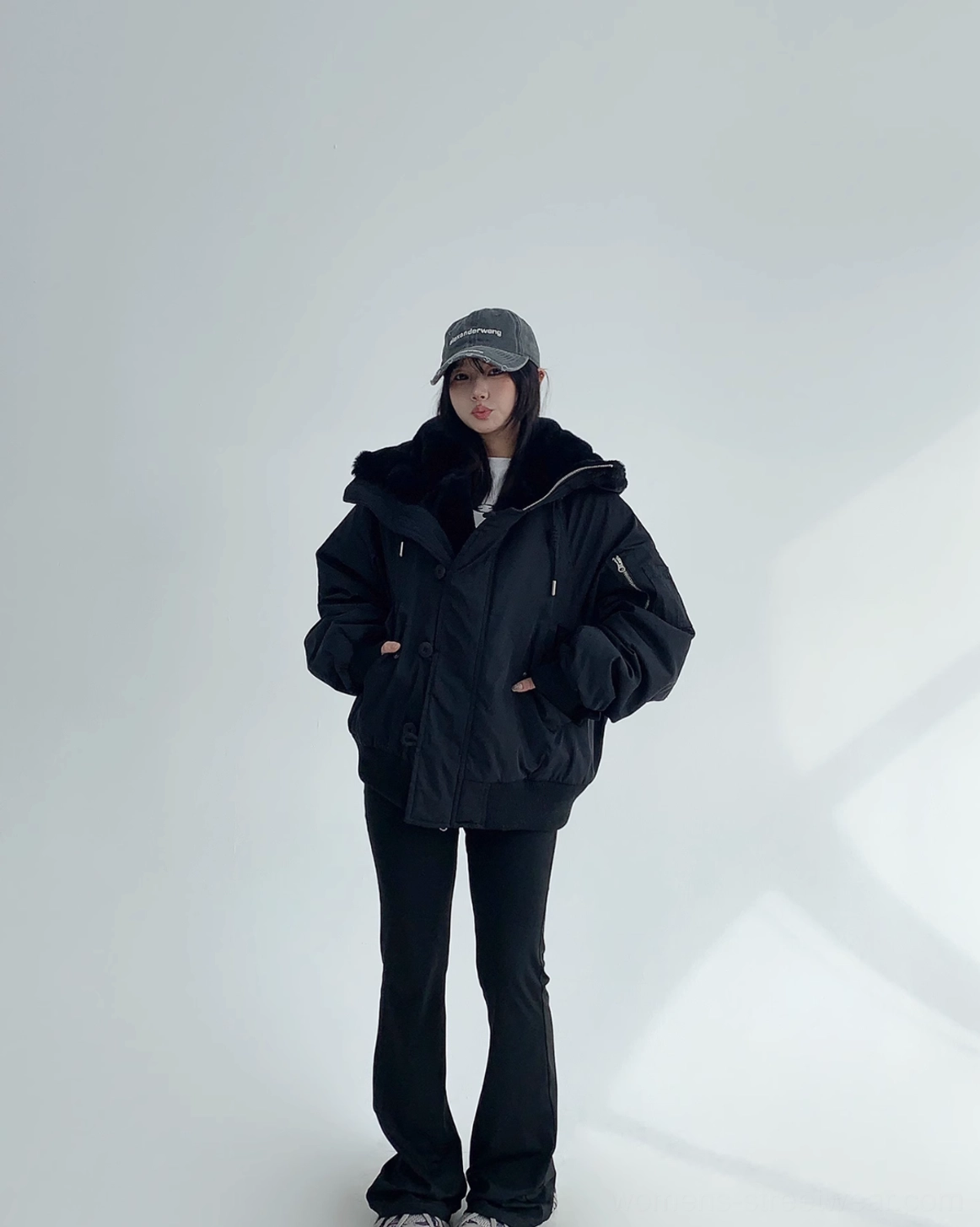 Black oversized winter bomber jacket with plush sherpa interior, adjustable hood, and relaxed drop-shoulder silhouette