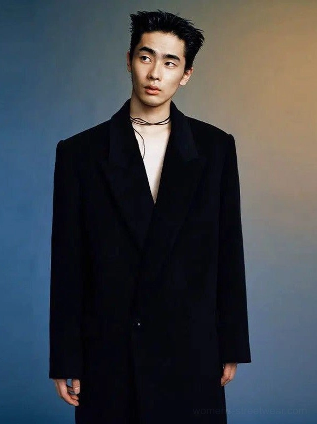 Black oversized wool peak lapel long coat shown from the front on a male model with a single-breasted silhouette and wide tailored lapels