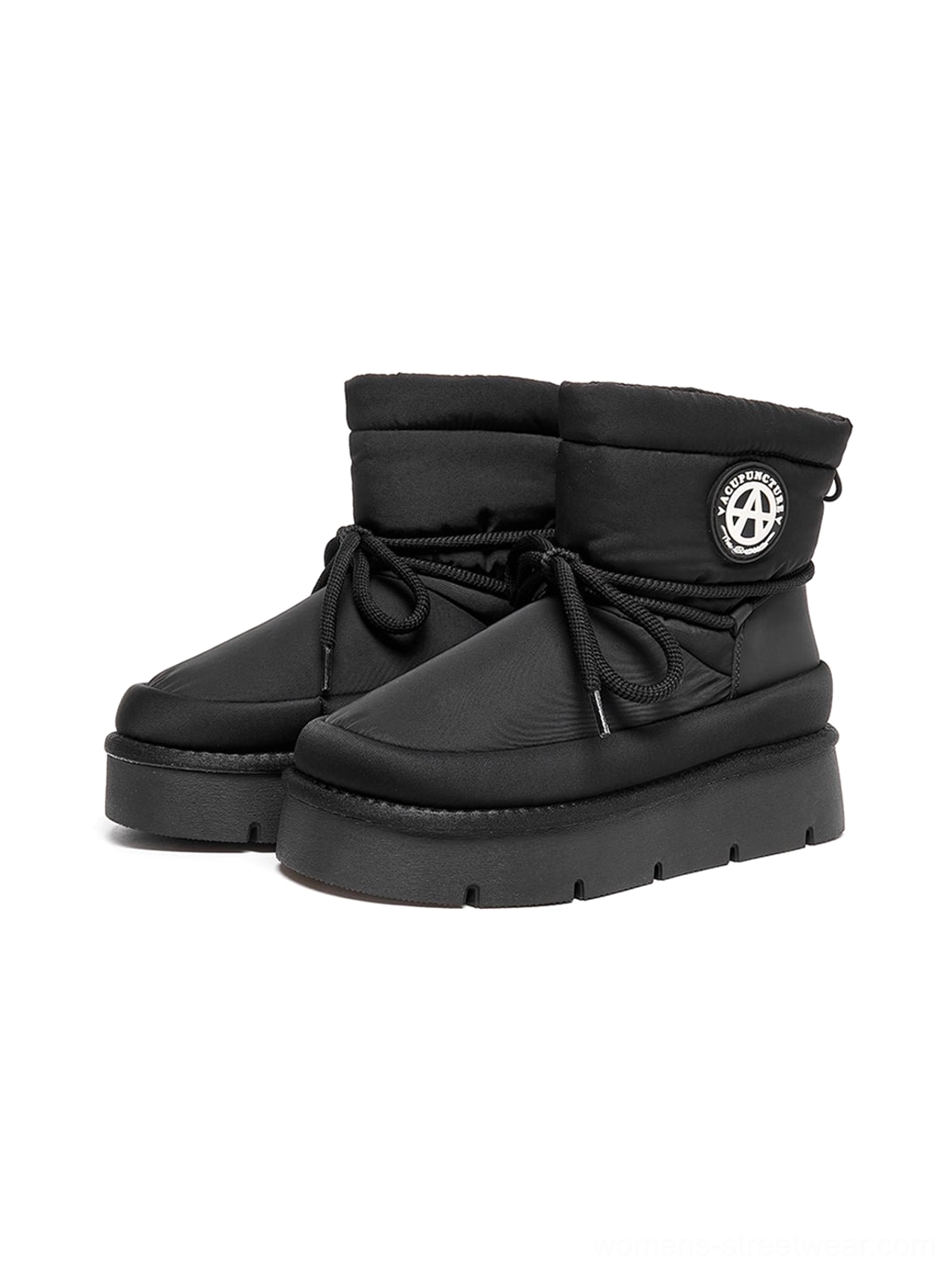 Pair of black padded platform snow boots in a dark studio display showing lace-up fronts and thick black rubber outsoles