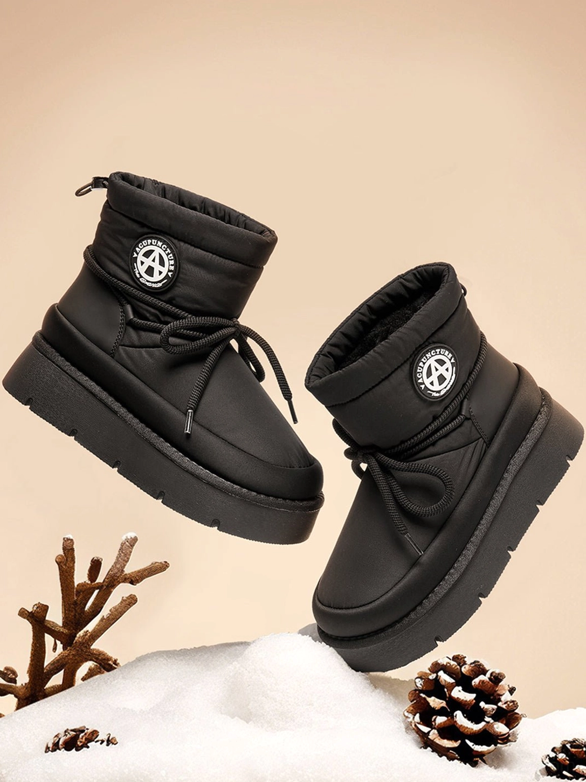 Floating pair of black padded platform snow boots with matte padded upper, lace-up front, and thick rubber sole