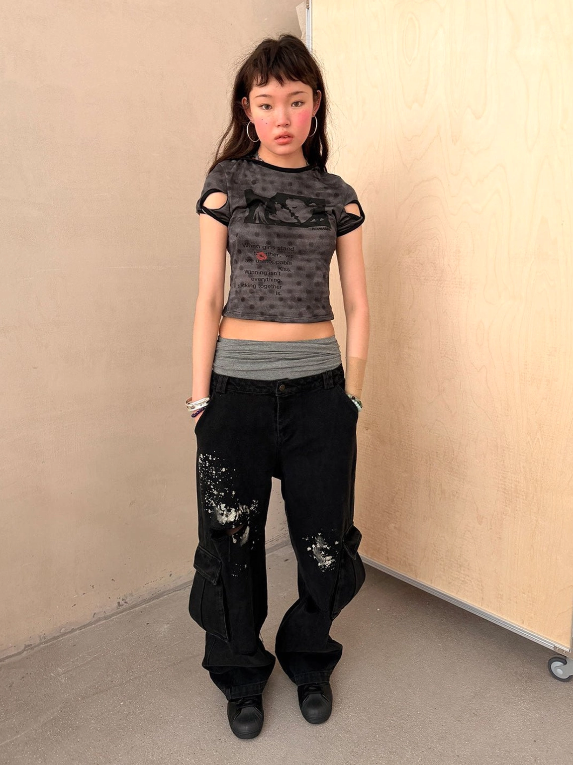 Black paint-splattered distressed cargo streetwear pants with ripped legs, utility pockets, and relaxed wide-leg fit