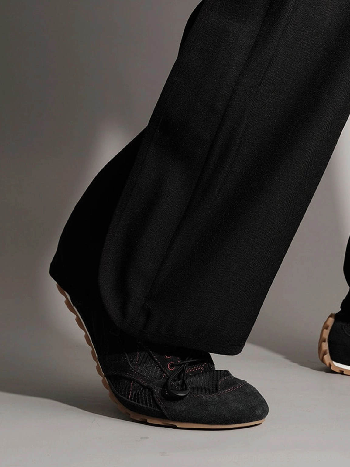 Rear three-quarter view of black paneled nubuck trainers with lace-up upper