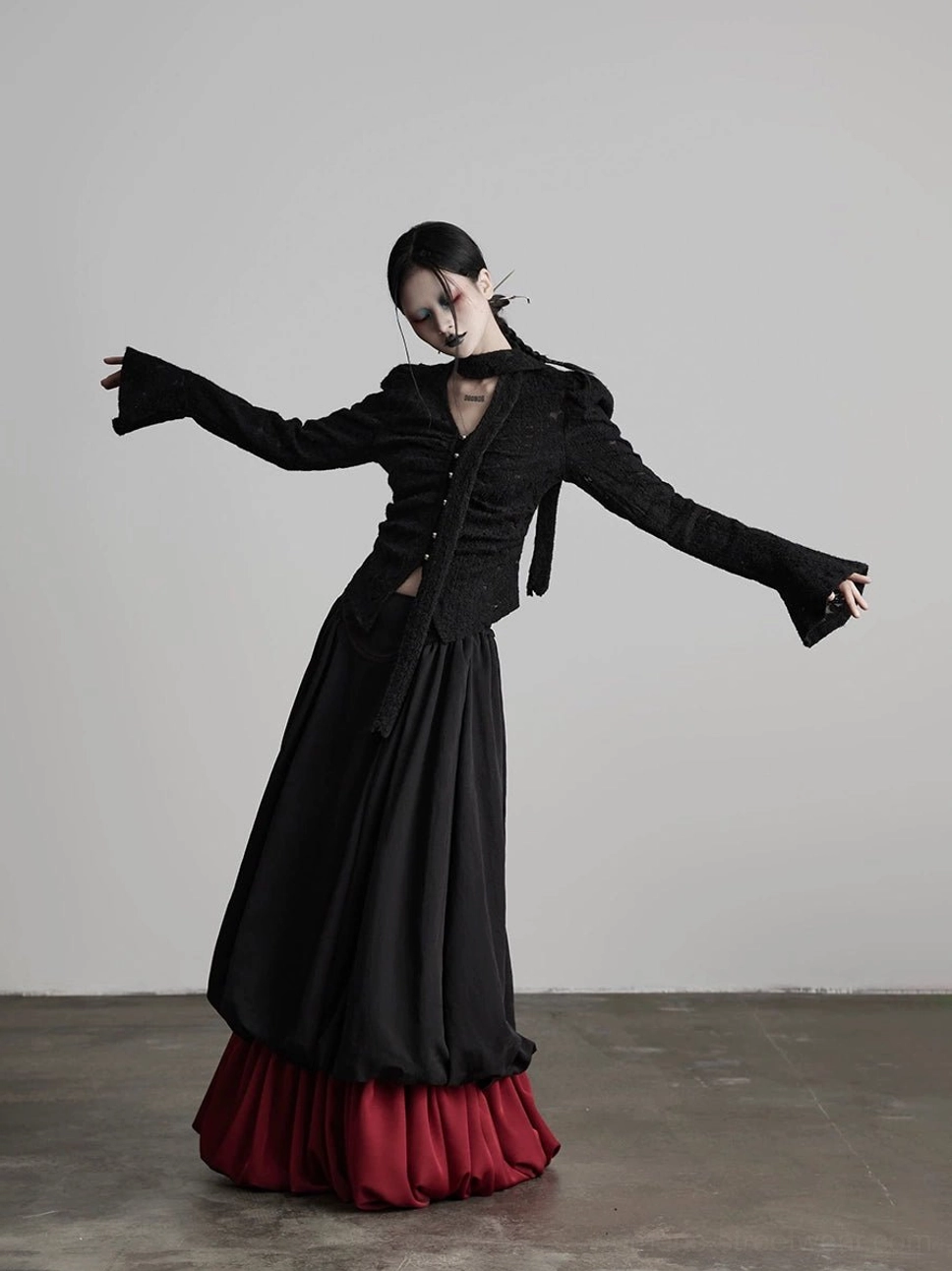 Front three-quarter view of black patchwork A-line maxi skirt with wine red ruffle hem