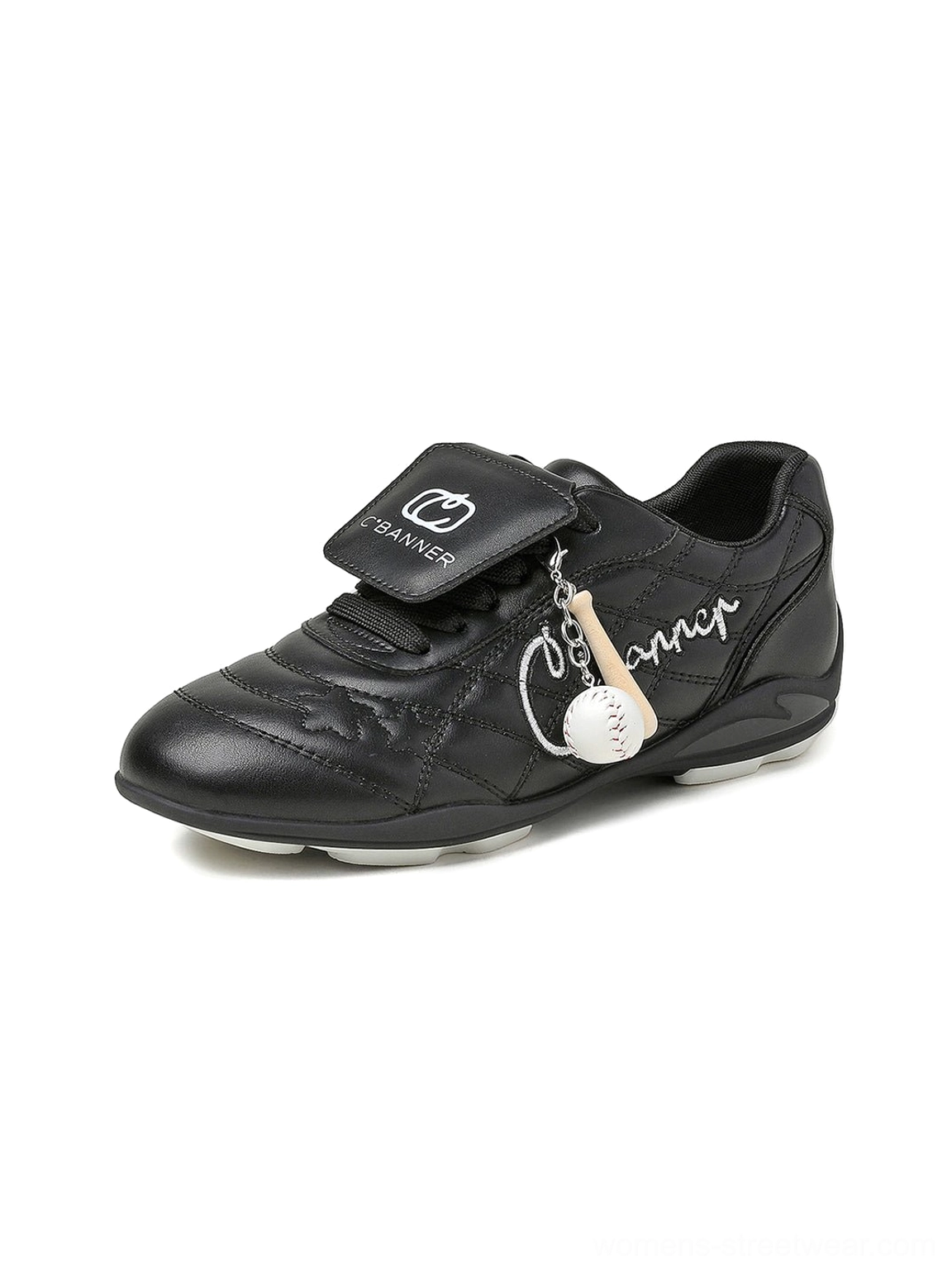 Black patent foldover tongue retro sneaker close-up with quilted upper side lettering and baseball-inspired charm
