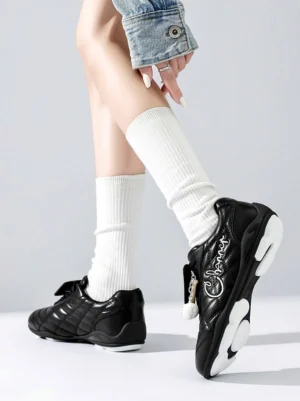 Model wearing black patent foldover tongue retro streetwear sneakers with white crew socks and denim
