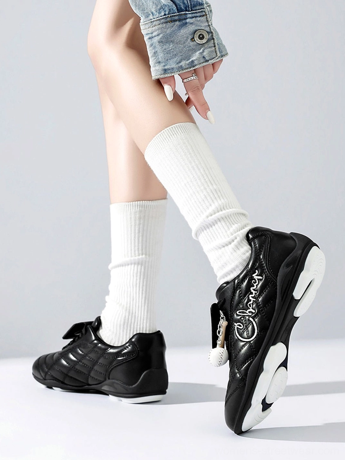 Model wearing black patent foldover tongue retro streetwear sneakers with white crew socks and denim