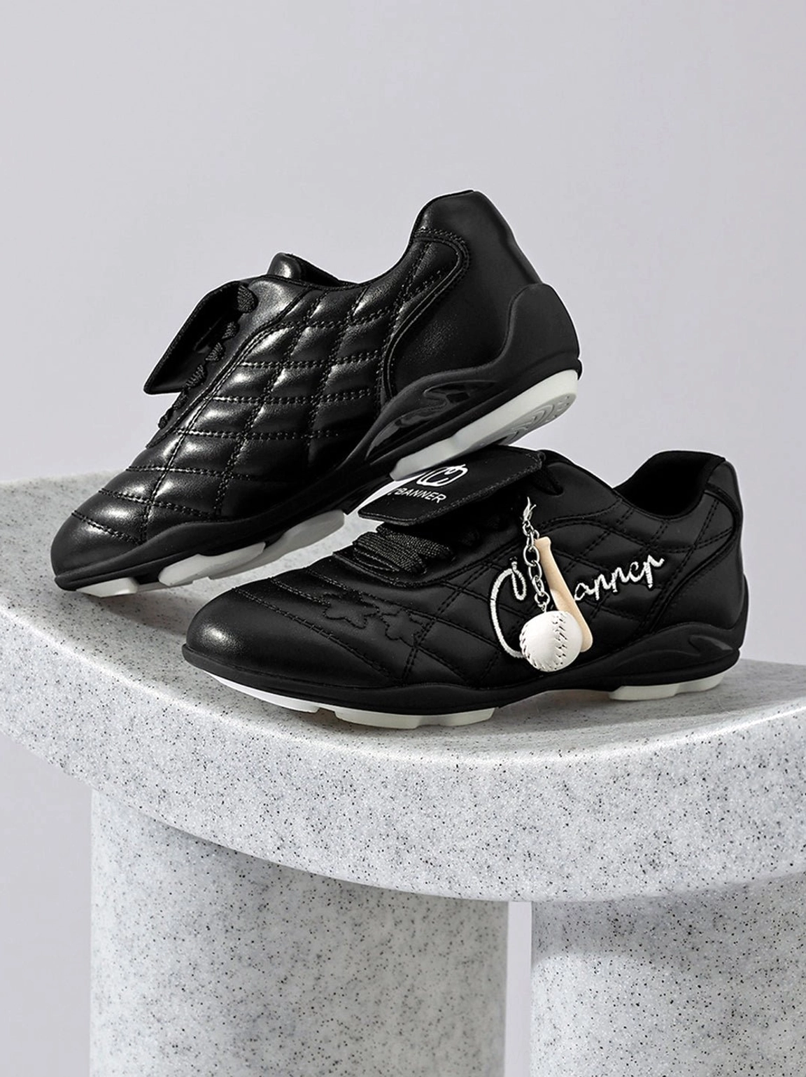 Black patent foldover tongue retro streetwear sneakers with quilted panels and metallic charm