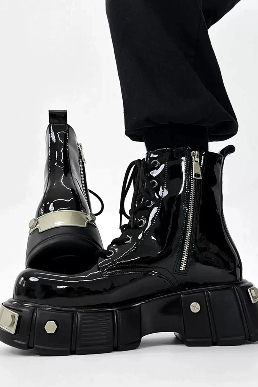 Black patent leather platform combat boots displayed in a side studio view with one boot raised, showing the side zipper, silver front sole plate, glossy finish, and chunky lug sole