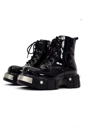Black patent leather platform combat boots in a front three-quarter studio view featuring glossy uppers, lace-up closures, chunky lug soles, and silver metal hardware