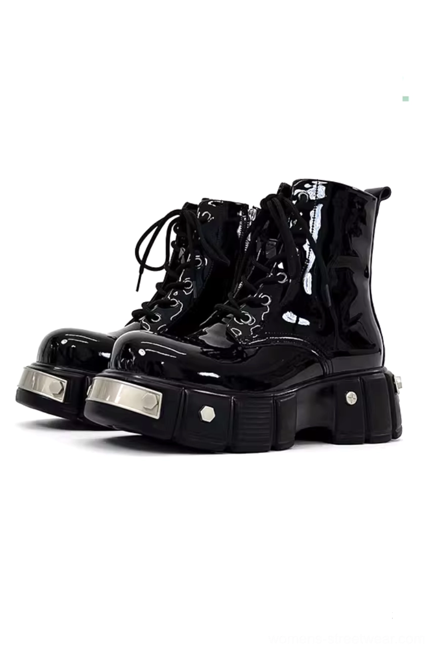 Black patent leather platform combat boots in a front three-quarter studio view featuring glossy uppers, lace-up closures, chunky lug soles, and silver metal hardware