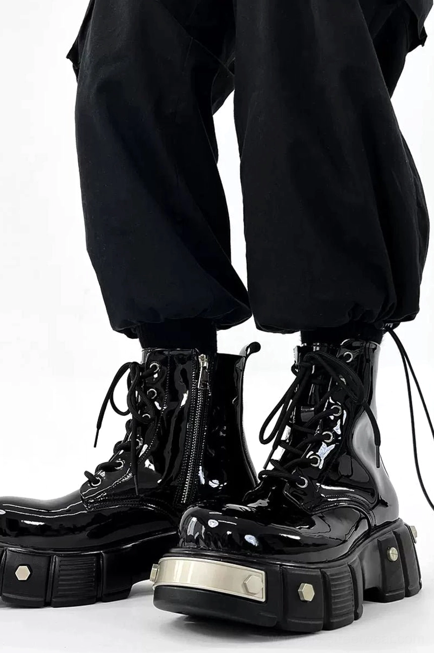 Black patent leather platform combat boots worn with cropped cargo pants, highlighting the side zipper, hexagonal sole rivets, silver hardware, and lug platform outsole