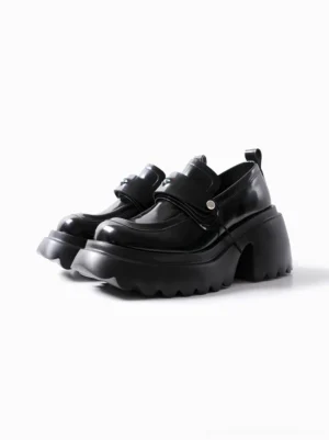 Black patent platform loafers with chunky lug sole, decorative buckle strap, detachable eye accent, and structured streetwear design