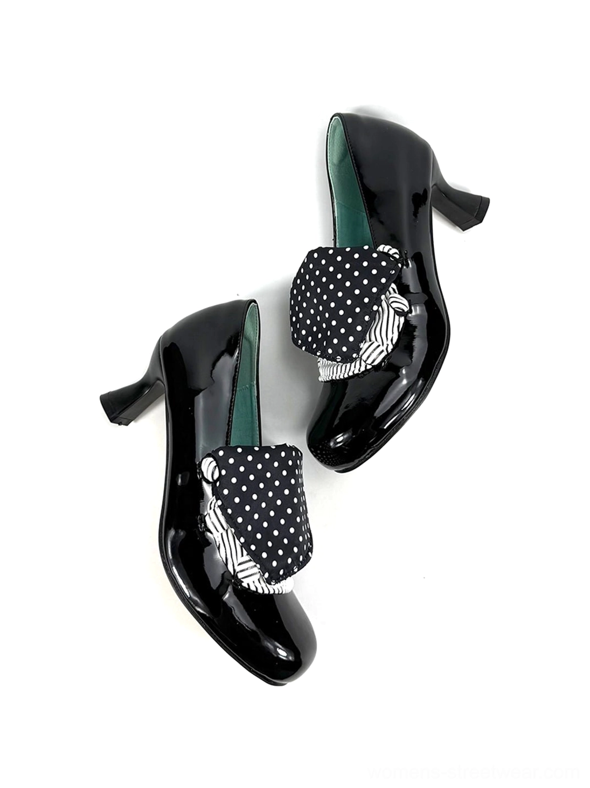 Crossed pair of black patent polka dot bow mid-heel pumps showing striped bow trim and curved block heels