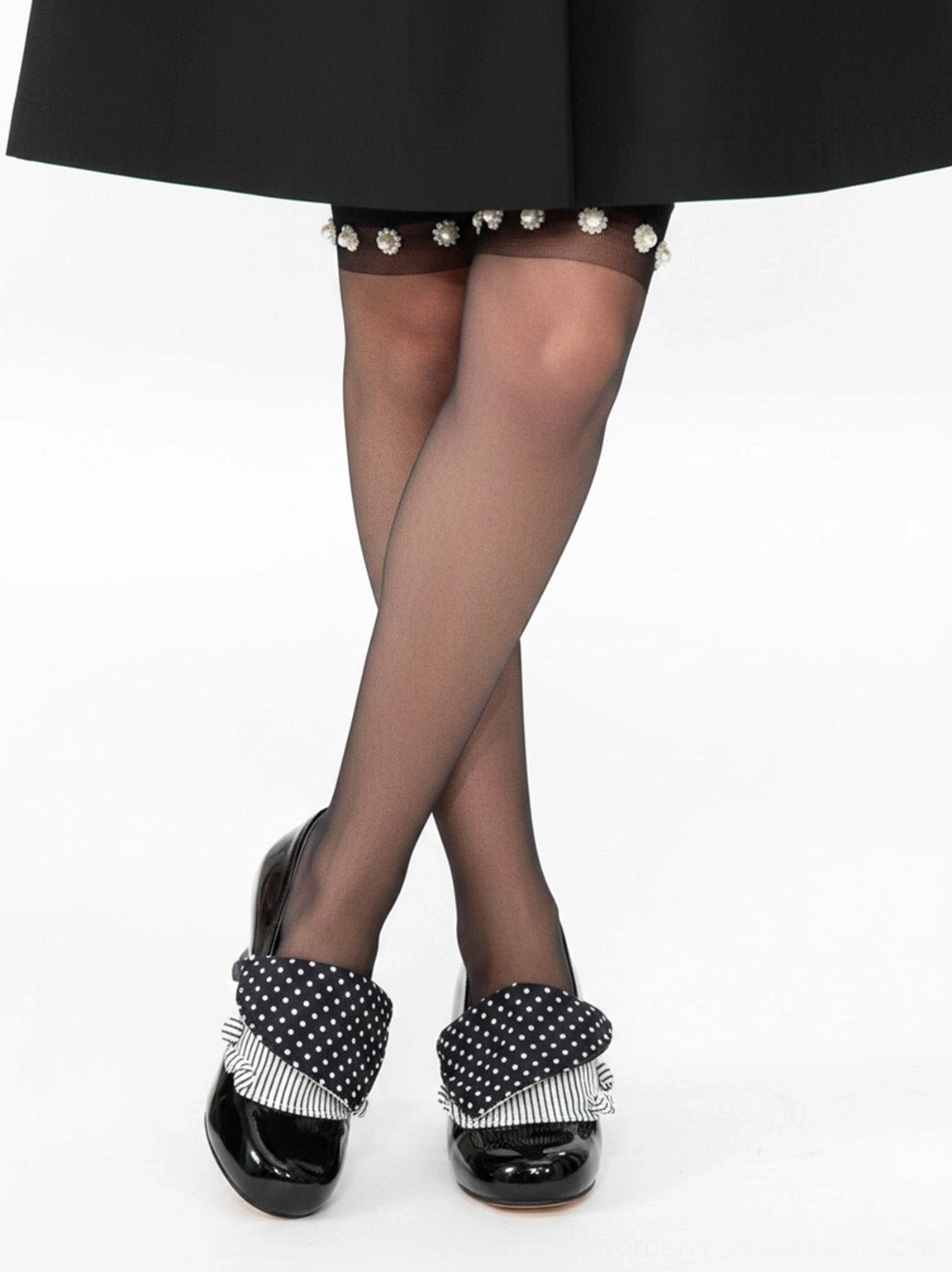 Black patent polka dot bow pumps styled with a black mini skirt and pearl-trim thigh-high stockings