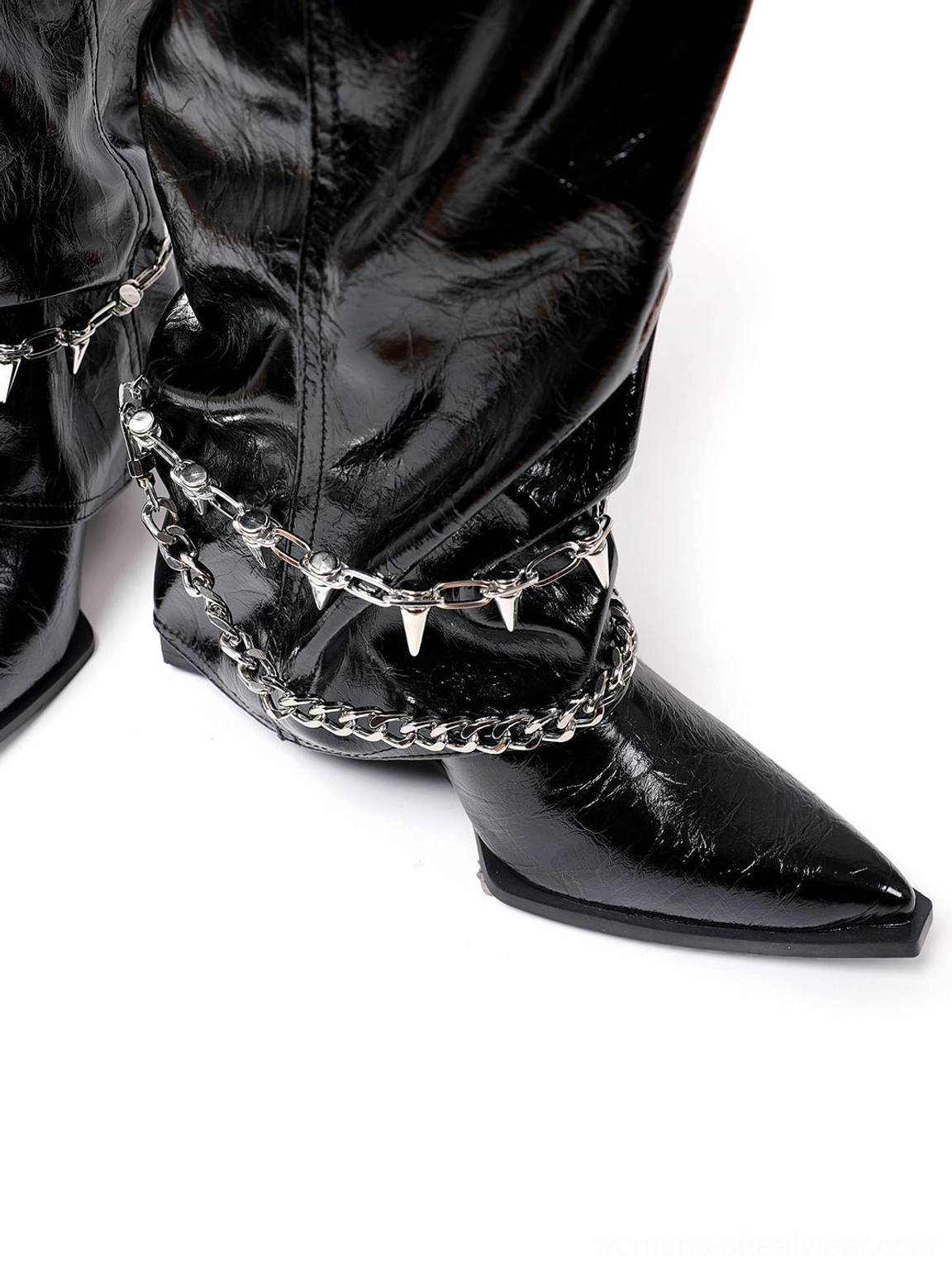 Side close-up of black patent spiked chain mid-calf punk wedge boot showing ankle hardware and pointed toe