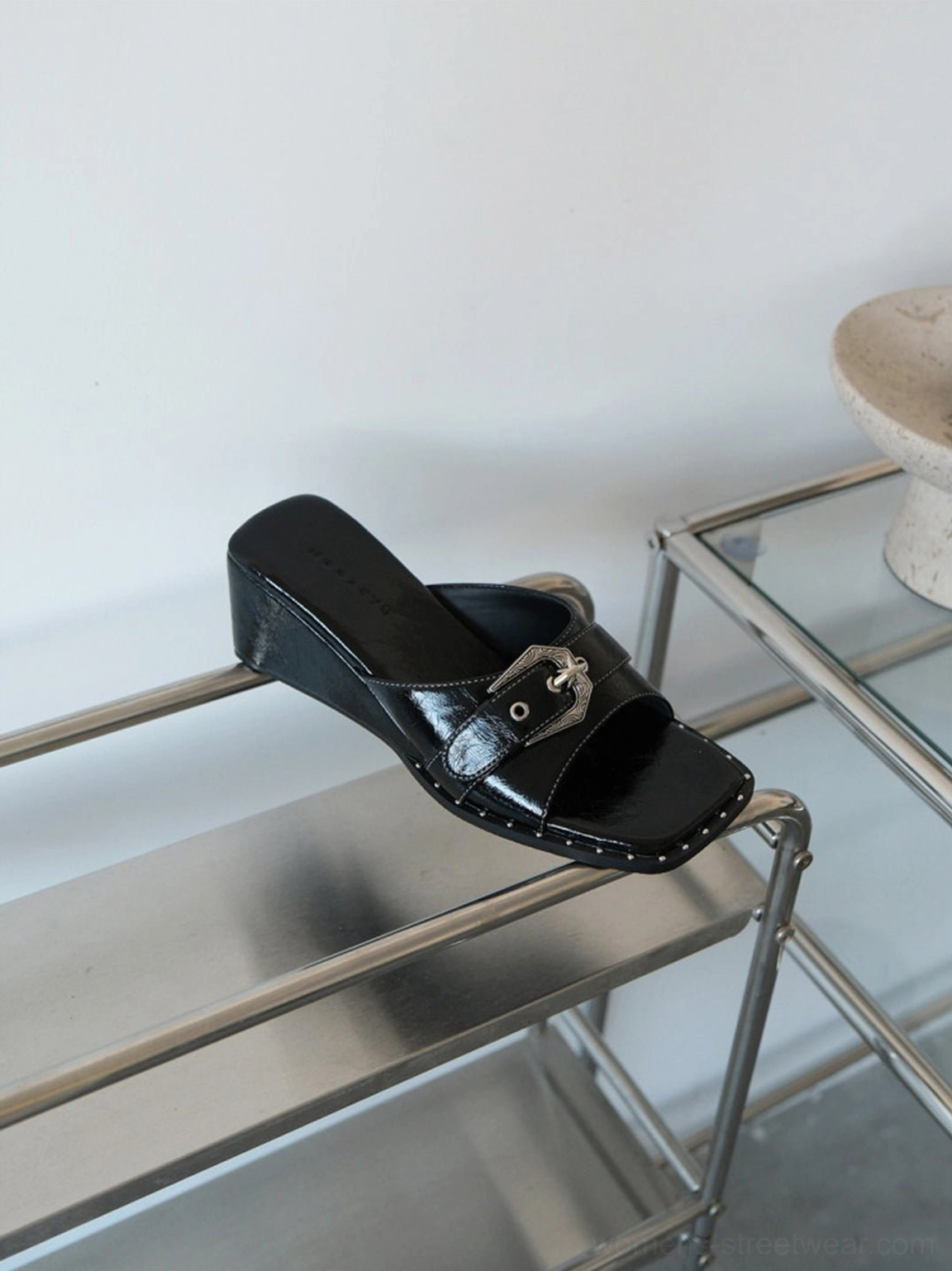 Three-quarter product view of black patent square-toe wedge slide sandals showing studded sole trim and open toe design