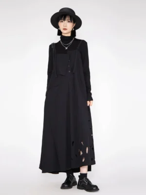 Full front view of black pinafore maxi dress with water-drop hem cutouts, spaghetti straps, button details, layered necklaces, and leather loafers