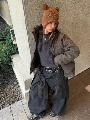 Female model in black washed plaid drape barrel jeans styled with a bear ear knit beanie for Korean streetwear fashion