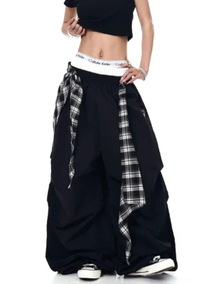 Front view of black plaid shroud parachute wide-leg streetwear cargo pants with oversized ruched legs, elastic waistband, and cropped top styling