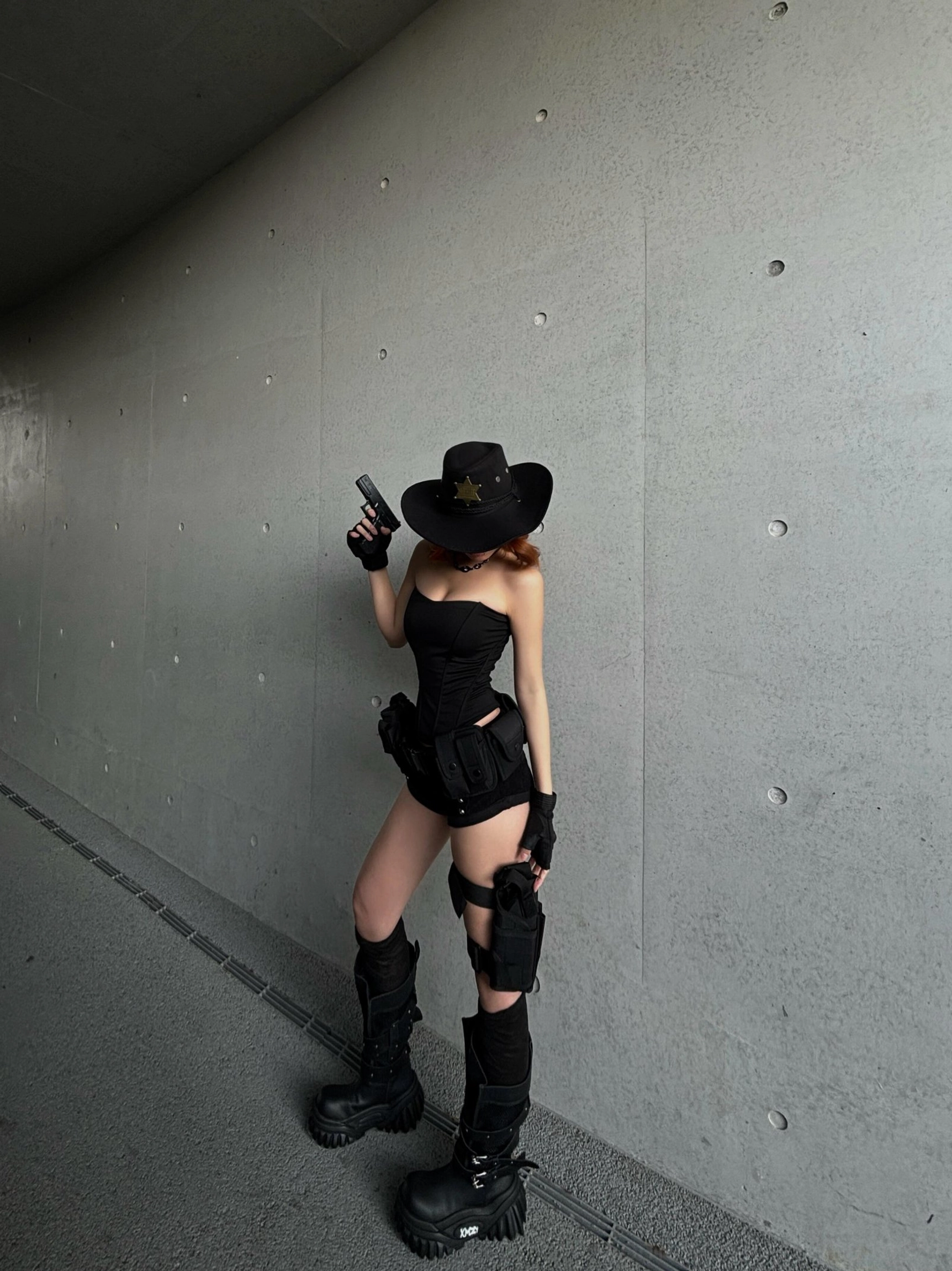 Black platform combat boots styled with an all-black tactical streetwear outfit in an industrial concrete corridor for a bold gothic techwear look