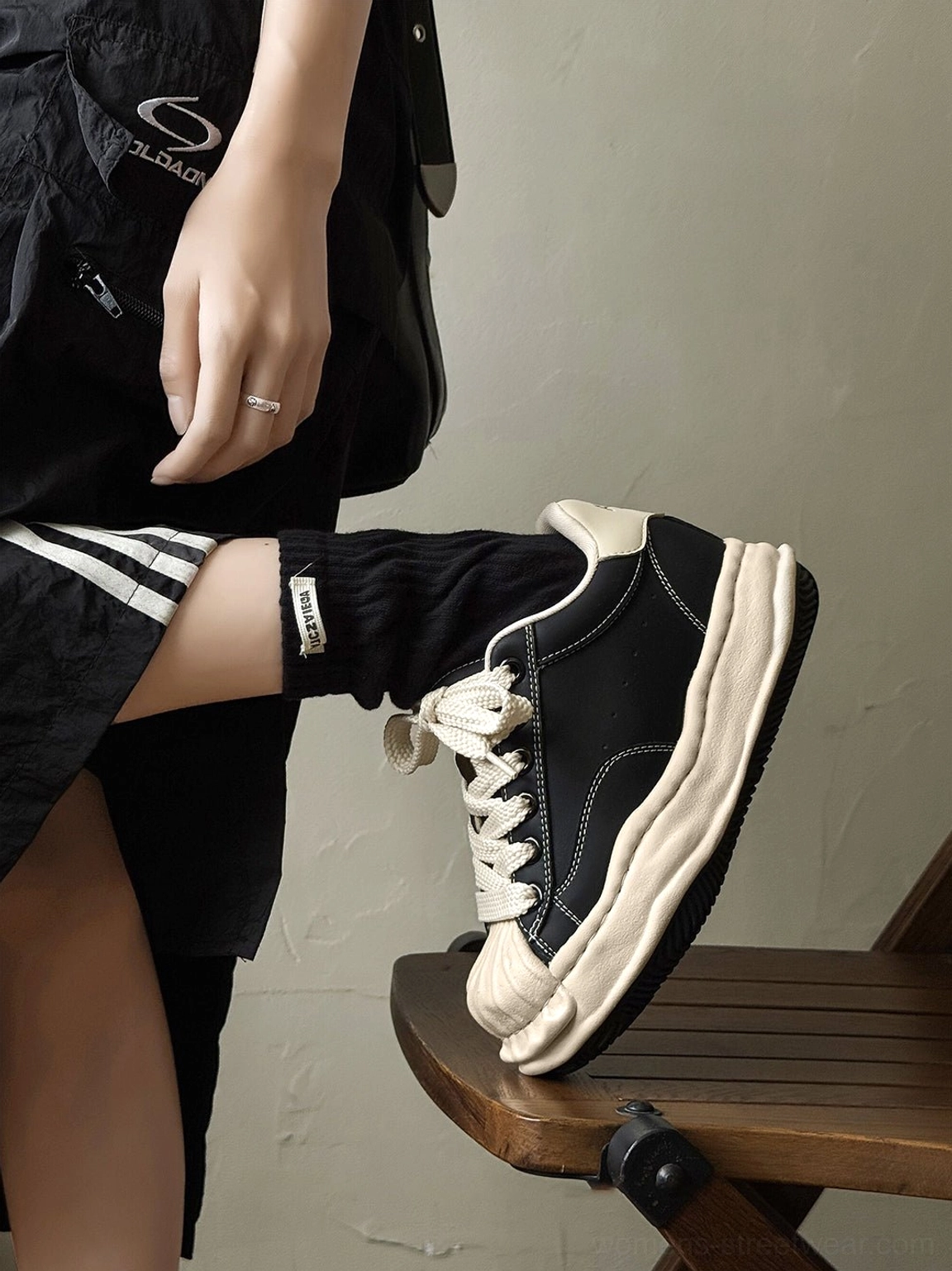 Side close-up of black platform court sneakers showing lace-up details, distressed overlays, and raised sole edge