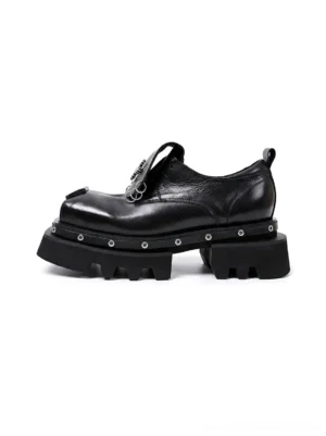 Black platform Derby shoes with glossy leather-look upper, square toe, chunky lug sole, and silver rivet detailing on a white background