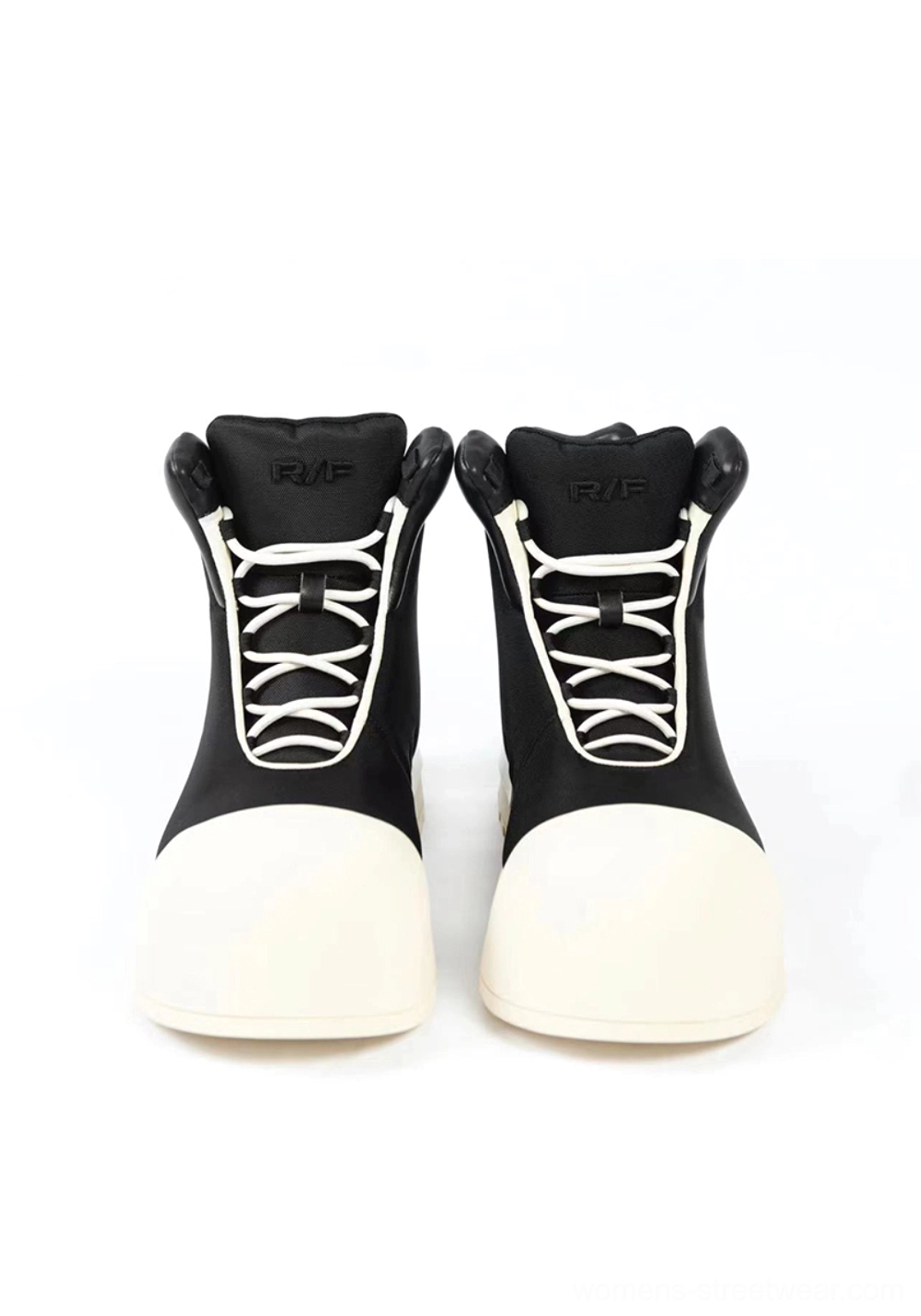 Front view of black platform high-top boots showing matching white laces, oversized off-white toe caps, padded tongues, and bold two-tone design