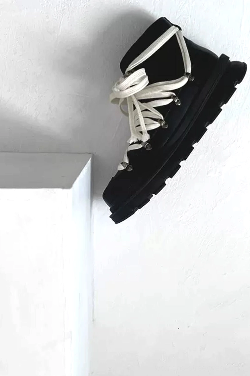 Low-angle black platform hiking combat boot on a white cube showing matte cowhide finish, contrast laces, thick platform, and anti-slip lugged outsole