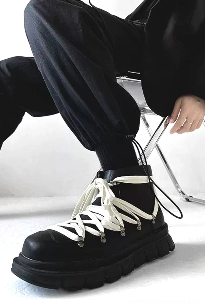 Side view of black platform hiking combat boots worn with baggy cropped black cargo trousers, showing high-top fit, contrast laces, and rugged sole