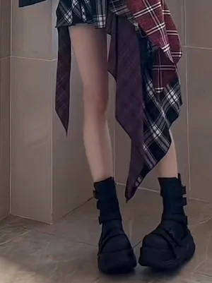 Black chunky platform motorcycle boots worn with socks and a Y2K plaid skirt outfit in a low-angle streetwear fashion view