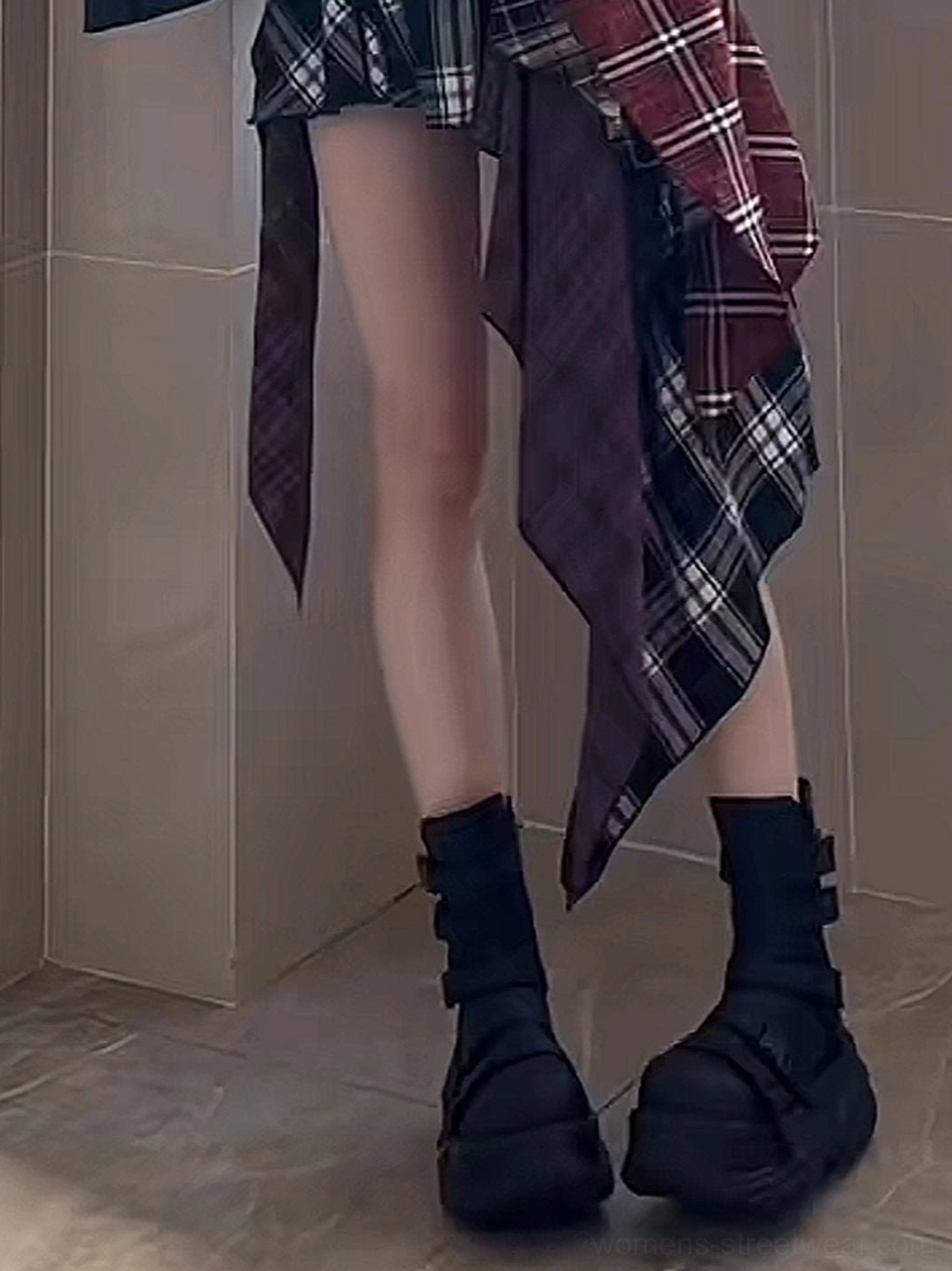 Black chunky platform motorcycle boots worn with socks and a Y2K plaid skirt outfit in a low-angle streetwear fashion view