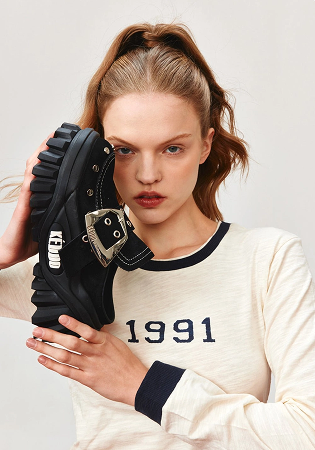 Close-up of black platform mule shoes with studded buckle detailing styled with a graphic long-sleeve streetwear outfit