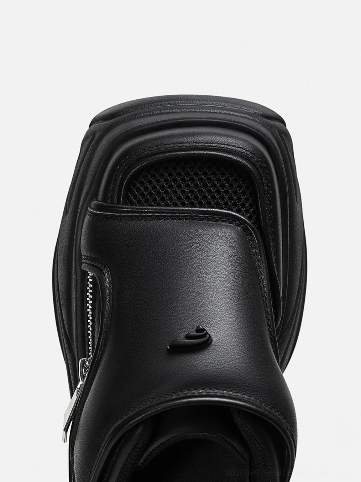 Close-up of a black platform slide sandal showing mesh covered toe, padded adjustable hook-and-loop strap, silver side zipper, and small metal detail