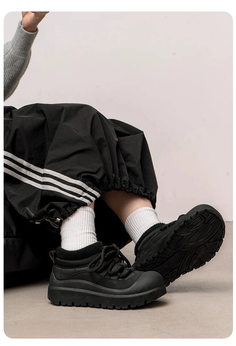 Low-angle lifestyle view of black fleece-lined platform sneakers styled with striped track pants and white crew socks
