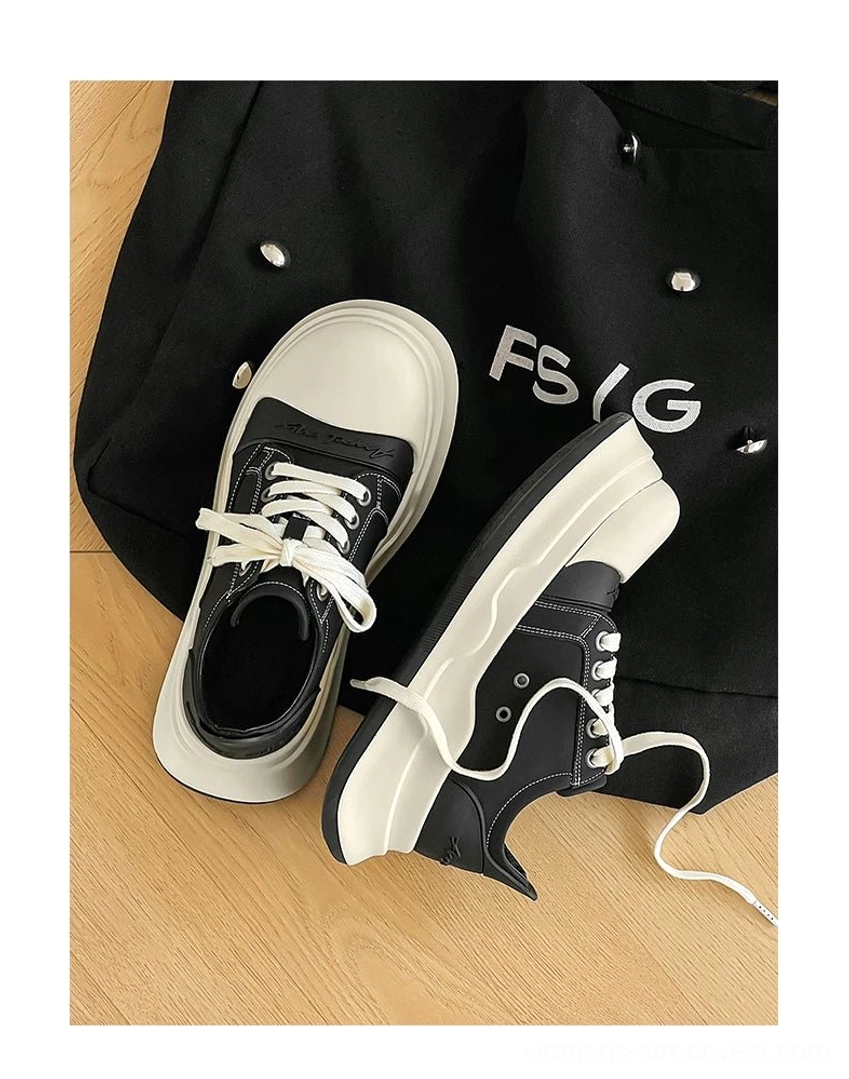 Top-down flat lay of black and off-white platform sneakers with loose white laces displayed beside a black tote bag on a wood surface
